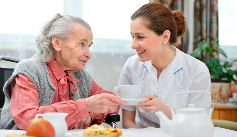 Personnel soignant donnant son petit-déjeuner à une personne âgée